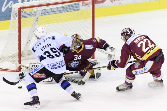 Le joueur fribourgeois, Andrey Bykov, gauche, a la lutte pour le puck avec le joueur genevois, Jonathan Mercier, droize, devant le gardien genevois, Gauthier Descloux, centre, lors du match du champio ...