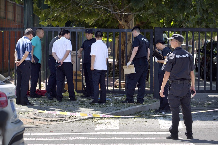 Officials and security personnel stand near the site of reported blast just south of the U.S. Embassy in Beijing, Thursday, July 26, 2018. A fire or possible explosion appears to have taken place outs ...
