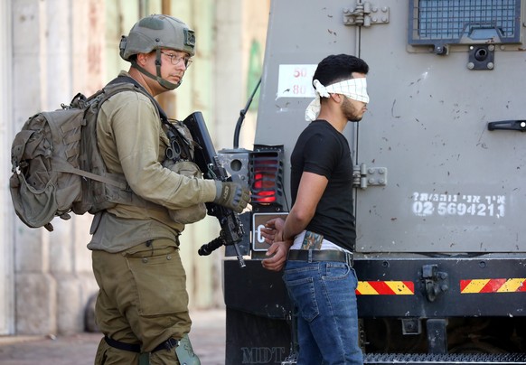 epa10173898 Israeli soldiers arrest a blindfolded Palestinian man during clashes following a protest in the city center of the West Bank city of Hebron, 09 September 2022. EPA/ABED AL HASHLAMOUN