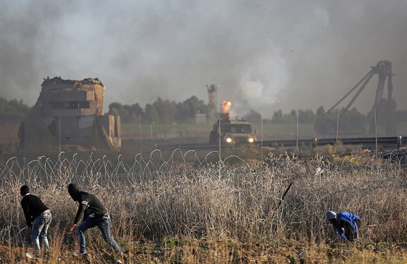 epa06377631 Palestinian protesters take cover while Israeli jeep fire tear-gaz during a protest against US President decision to recognize Jerusalem as the capital of Israel, during clashes along the  ...