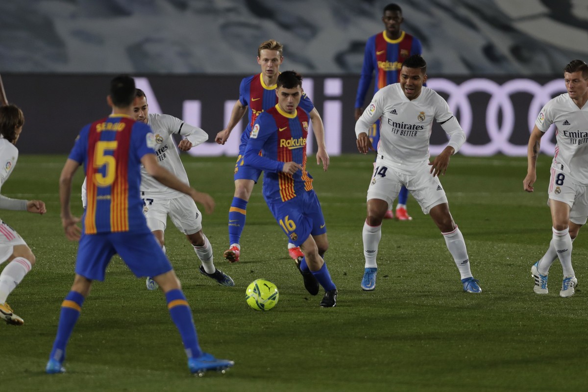 Barcelona's Pedri, center, plays the ball next to Real Madrid defenders during the Spanish La Liga soccer match between Real Madrid and FC Barcelona at the Alfredo di Stefano stadium in Madrid, S ...