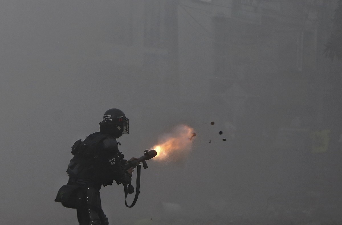 A police officer fires tear gas at protesters during a strike against tax reform in Cali, Colombia, Monday, May 3, 2021. Colombia's President Ivan Duque withdrew the government-proposed tax refor ...