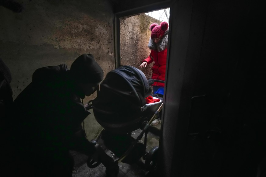 A couple enter a shelter with a baby in a stroller during Russian shelling outside Mariupol, Ukraine, Thursday, Feb. 24, 2022. (AP Photo/Sergei Grits)