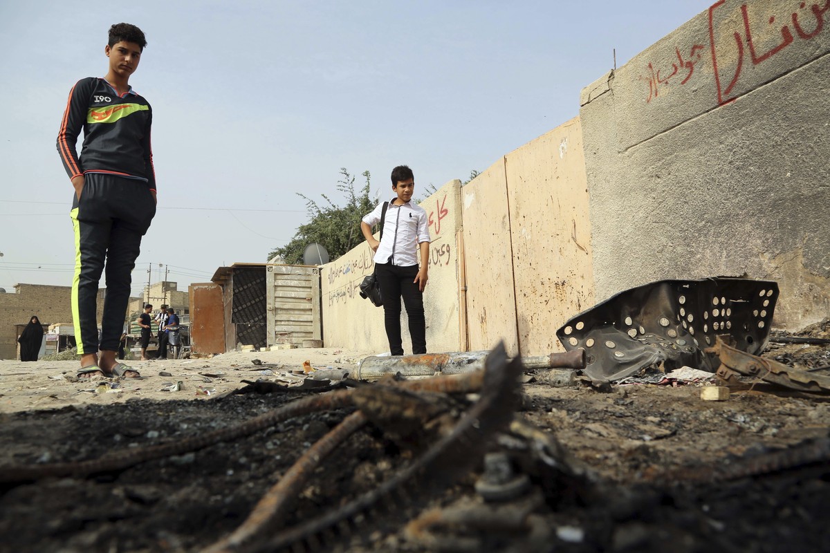 People inspect the aftermath of a deadly car bomb explosion that hit a popular fruit and vegetable market in a commercial street in Baghdad's northwestern neighborhood of Hurriyah, Iraq, Monday,  ...