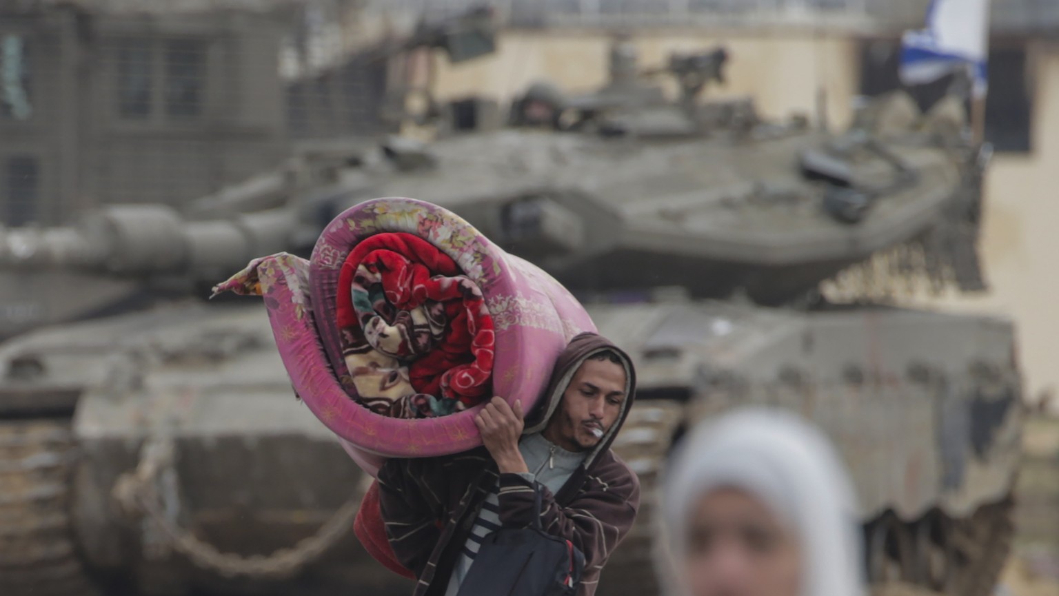 epa11108573 Internally displaced Palestinians move past Israeli tanks after the Israeli army told residents of Khan Yunis camp to leave their homes and head towards Rafah camps near the Egyptian borde ...