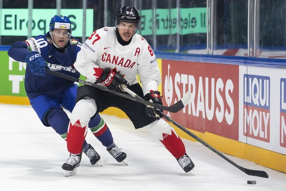 epa12964113 Italy's Peter Spornberger, left, vies for the puck against Canada's Sidney Crosby, right, during the 2026 IIHF Men's Ice Hockey World Championship preliminary round group B  ...