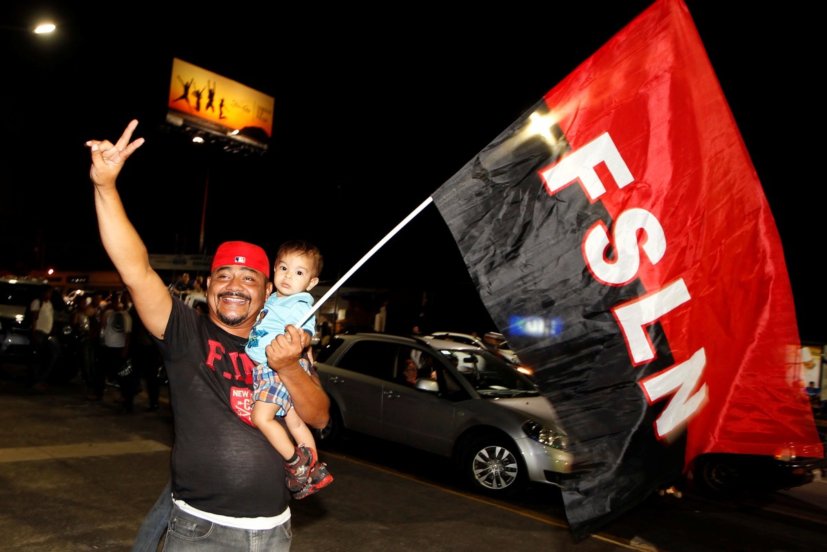 A supporter of Nicaragua's President Daniel Ortega and vice presidential candidate, his wife, Rosario Murillo, holds up a flag of the Sandinista National Liberation Front, or FSLN, while celebrat ...
