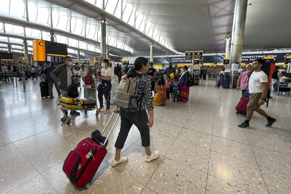 Travellers at Heathrow airport, in London, Wednesday, July 13, 2022. Heathrow Airport has introduced a cap on passenger numbers this summer as the aviation sector struggles to cope with demand for tra ...