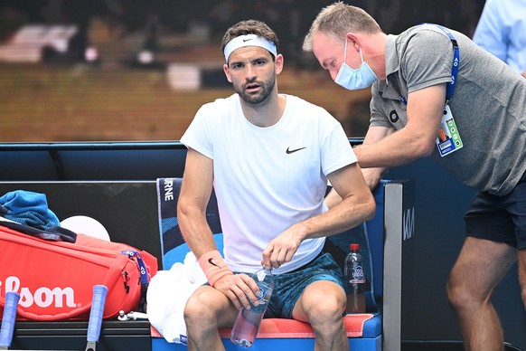 epa09015436 Grigor Dimitrov (L) of Bulgaria reveives medical treatment during his Quarterfinals Men's singles match against Aslan Karatsev of Russia at the Australian Open Grand Slam tennis tournament ...