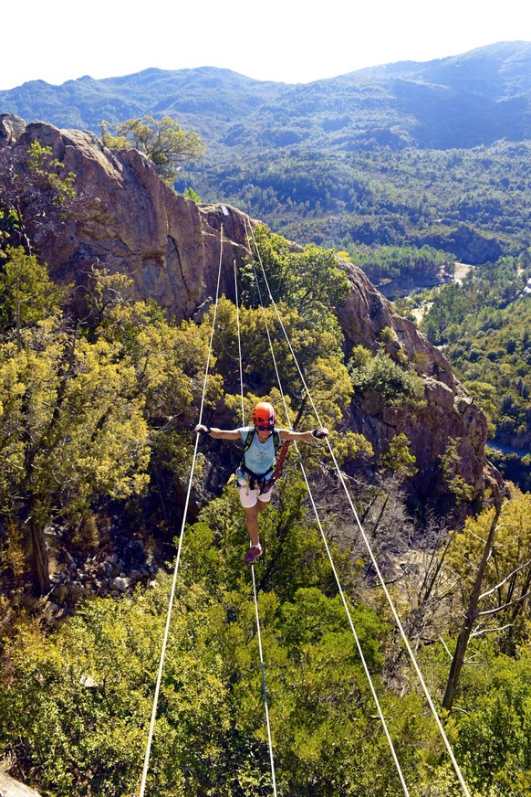 Kletterer ueberquert eine Schlucht auf einem Drahtseil, Klettersteig A Buccarona, Frankreich, Korsika, Solenzara climber crossing a canyon on a wire rope, via ferrata A Buccarona, France, Corsica, Sol ...