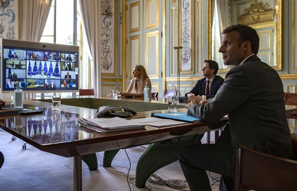 epa08379773 French President Emmanuel Macron (R) attends a video conference call with members of the European Council at the Elysee Palace in Paris, France, 23 April 2020. Countries around the world a ...