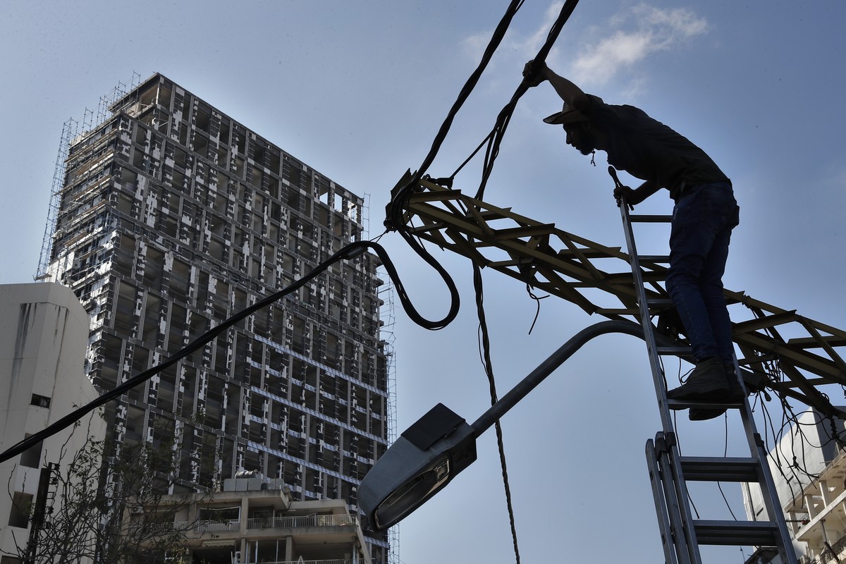 A electricity worker fixes power cables in front of a damaged building, near the scene of Tuesday's explosion that hit the seaport of Beirut, Lebanon, Friday, Aug. 7, 2020. Rescue teams were stil ...