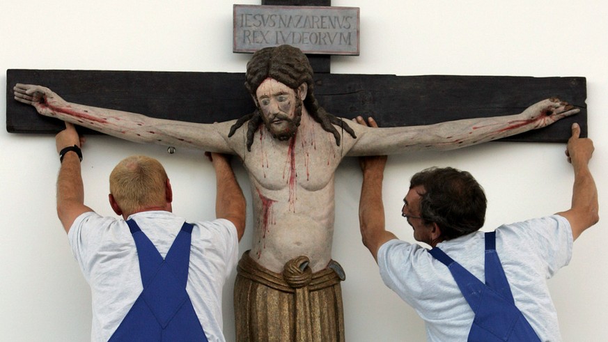 Workers suspend the 1100-year-old crucifix from the church of the village of Enghausen, Bavaria, above the altar on the fair grounds in Munich, southern Germany, Thursday, Sept. 7, 2006, where pope Be ...