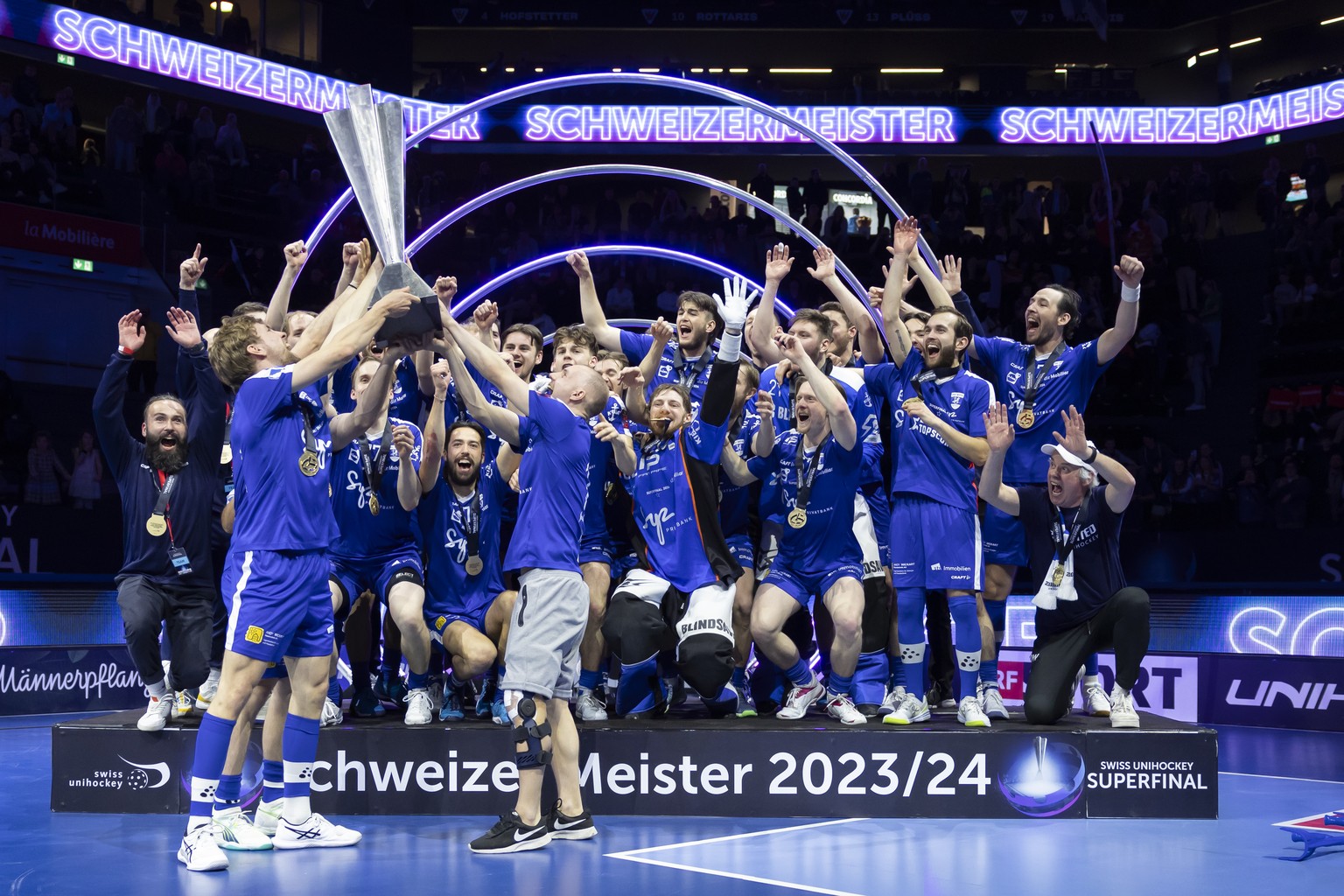 Die Zuger Spieler jubeln mit dem Pokal nach dem Sieg im Swiss Unihockey Superfinal der Herren zwischen Zug United und SV Wiler-Ersigen, am Sonntag, 21. April 2024 in Fribourg. (KEYSTONE/Peter Klaunzer ...