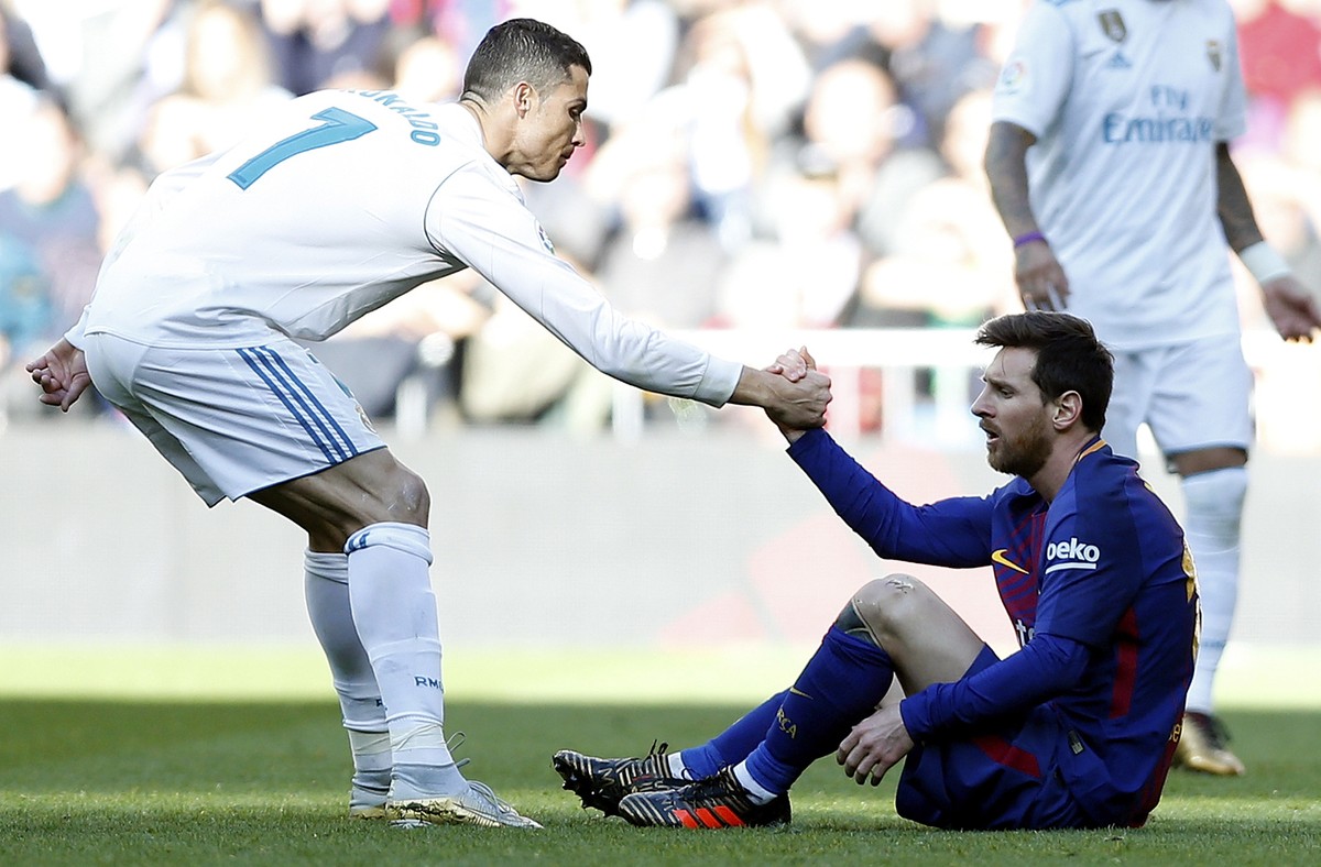 Real Madrid's Cristiano Ronaldo, left, helps Barcelona's Lionel Messi get back on his feet during the Spanish La Liga soccer match between Real Madrid and Barcelona at the Santiago Bernabeu  ...