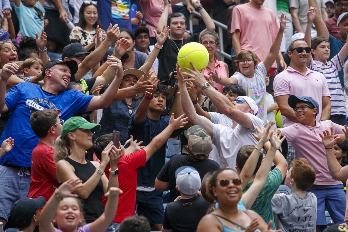 epa10822358 The crowd attempts to catch a large tennis ball thrown into the audience during Arthur Ashe Kids' Day at Arthur Ashe Stadium in the USTA National Tennis Center in Flushing Meadows, Ne ...