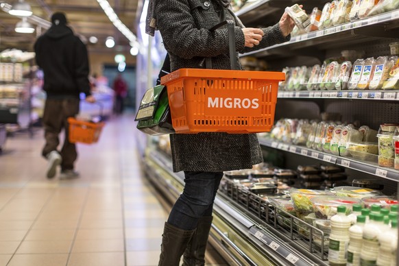 ZU DEN UMSATZZAHLEN 2013 DER MIGROS-GRUPPE STELLEN WIR IHNEN FOLGENDES THEMENBILD ZUR VERFUEGUNG - Eine Kundin mit einem Einkaufskorb nimmt ein Produkt aus dem Kuehlregal, aufgenommen am 5. Maerz 2013 ...