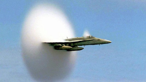 An F/A-18 Hornet assigned to Strike Fighter Squadron One Five One (VFA-151) emerges from a cloud caused when it broke the sound barrier in the skies over the Pacific Ocean, July 7, 1999. VFA-151 is cu ...