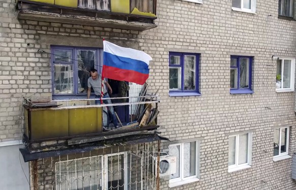Ausschnitt aus einem russischen Propaganda-Video: Ein Anwohner Lyssytschansks hisst die russische Flagge auf den Balkon. 
