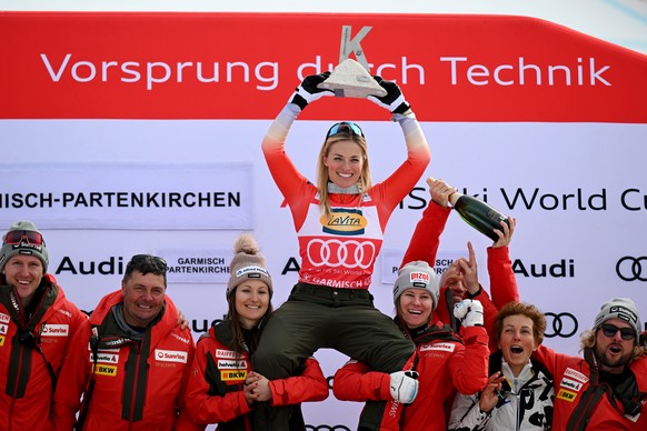 26.01.2025, Bayern, Garmisch-Partenkirchen: Ski alpin, Weltcup, Super G, Damen, Lara Gut-Behrami aus der Schweiz (o) jubelt bei der Siegerehrung �ber den ersten Platz zusammen mit dem Team. Foto: Ange ...