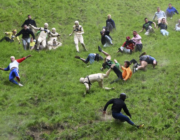 Participants compete in the men&#039;s downhill race category of the traditional annual Cheese Rolling contest at Cooper&#039;s Hill in Brockworth, Gloucestershire, England, Monday, May 26, 2025.(AP P ...