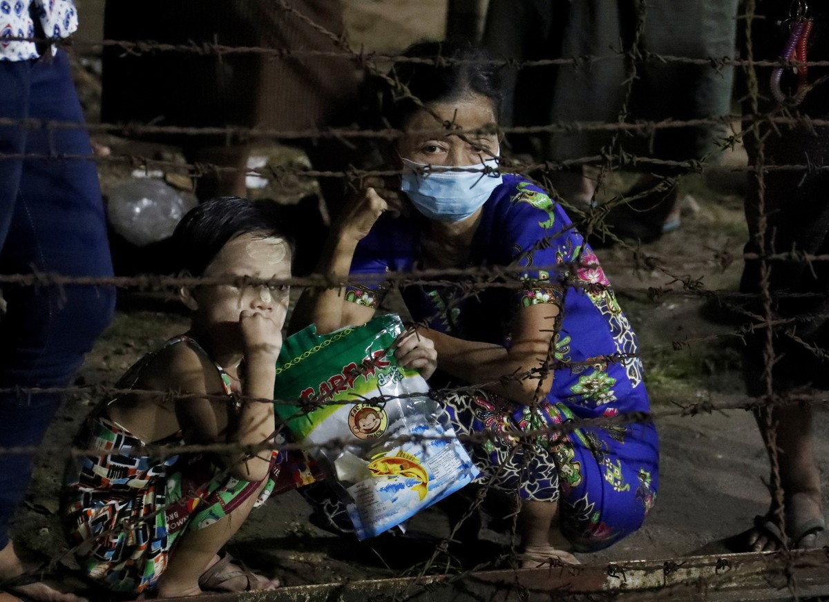 epa09530197 A woman and a girl wait for the released of their family member behind the barricade outside the Insein prison in Yangon, Myanmar, 18 October 2021. Myanmar's junta chief Min Aung Hali ...