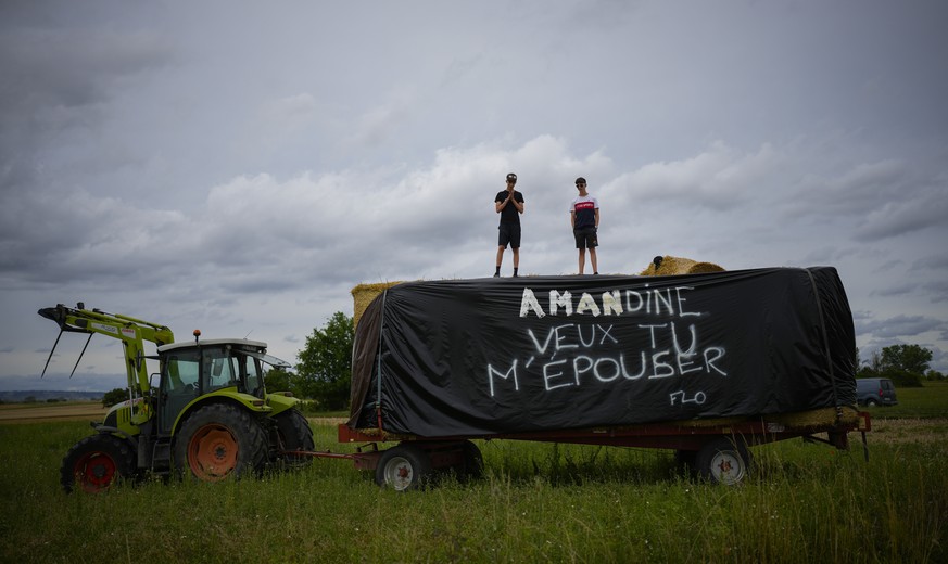 Two spectators stand on a flatbed with a marriage proposal reading "Amandine Do You Want To Marry Me", signed "Flo" during the eleventh stage of the Tour de France cycling race ove ...