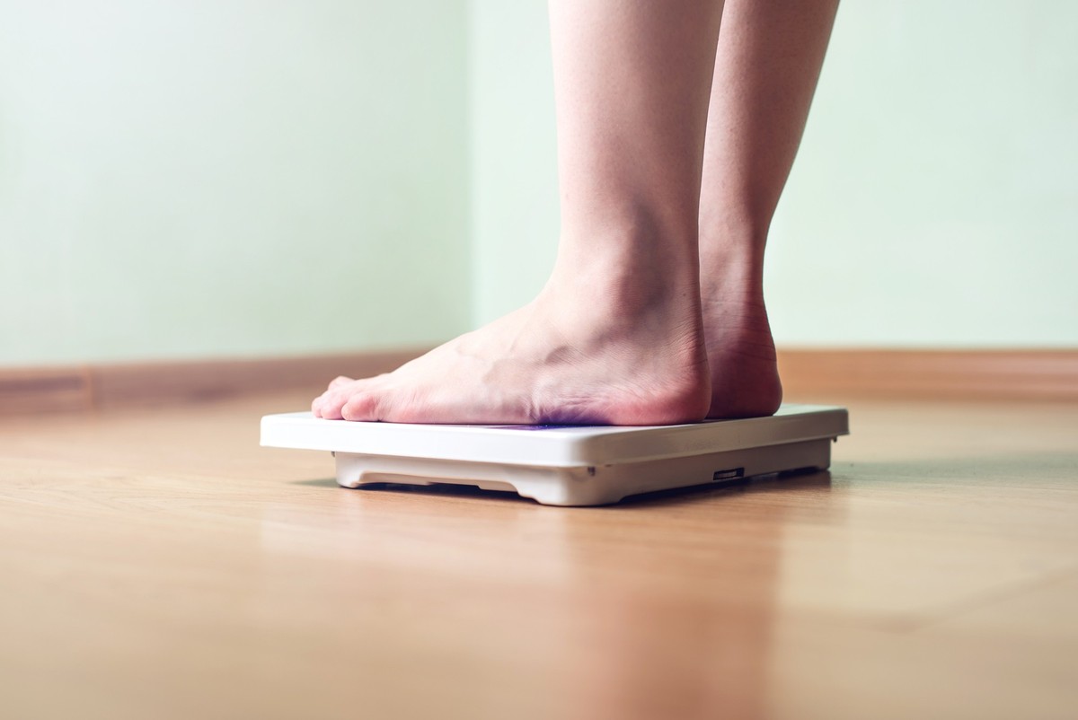 Women's feet are on mechanical scales for weight control on wooden background. The concept of slimming and weight loss