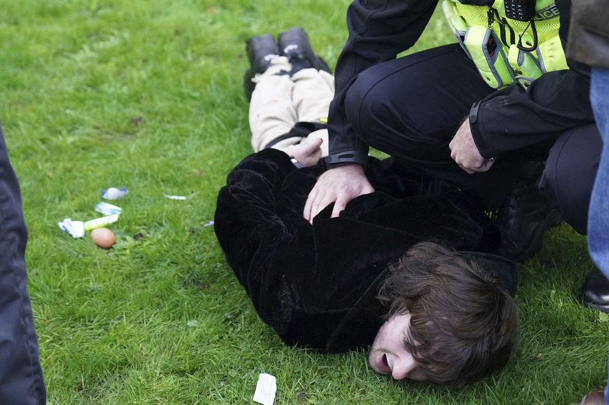 Police empty contents, including an unthrown egg, left, from the pockets of a protester, as they detain him for throwing eggs at Britain's King Charles III and Camilla, the Queen Consort, as they ...