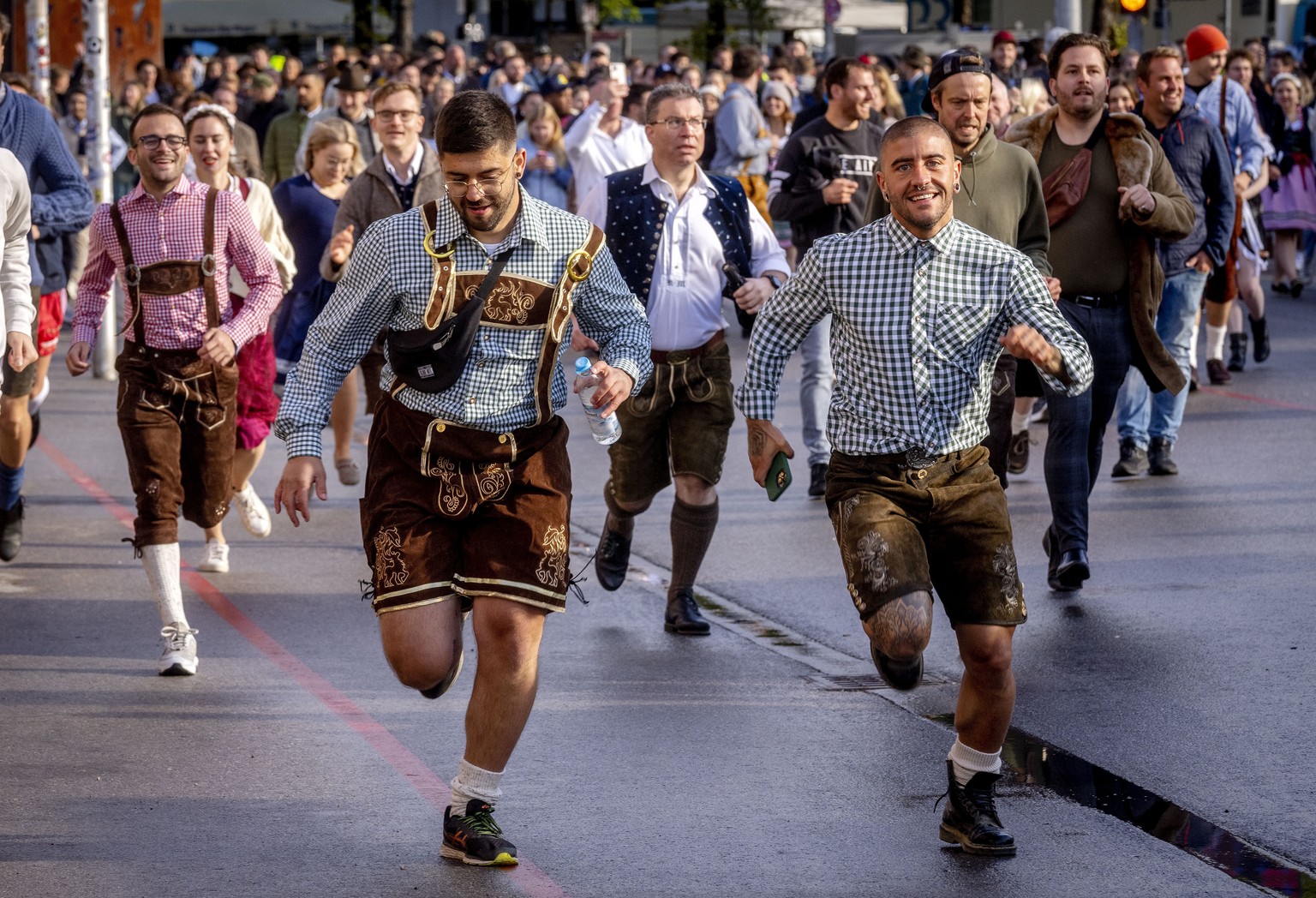 People run onto the festival ground on the opening day of the 187th Oktoberfest beer festival in Munich, Germany, Saturday, Sept. 17, 2022. Oktoberfest is back in Germany after two years of pandemic c ...