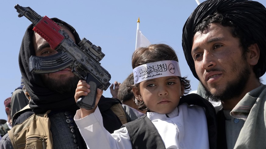 An Afghan boy holds a toy weapon during a celebration marking the first anniversary of the withdrawal of US-led troops from Afghanistan, in front of the U.S. Embassy in Kabul, Afghanistan, Wednesday,  ...