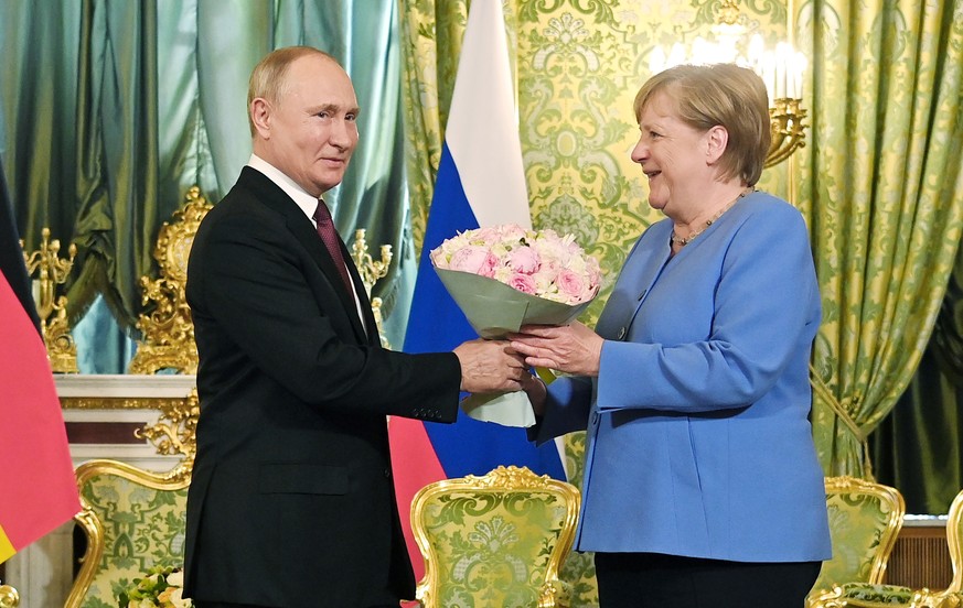 Russian President Vladimir Putin, left, presents flowers to German Chancellor Angela Merkel during their meeting in the Kremlin in Moscow, Russia, Friday, Aug. 20, 2021. The talks between Merkel and P ...