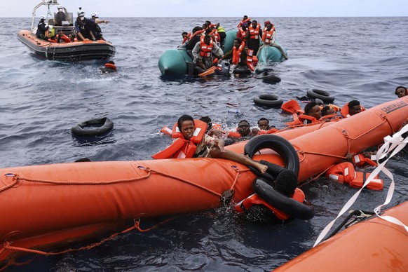 FILE - Migrants aboard a rubber boat end up in the water while others cling on to a centifloat before being rescued by a team of the Sea Watch-3, around 35 miles away from Libya, Monday, Oct. 18, 2021 ...