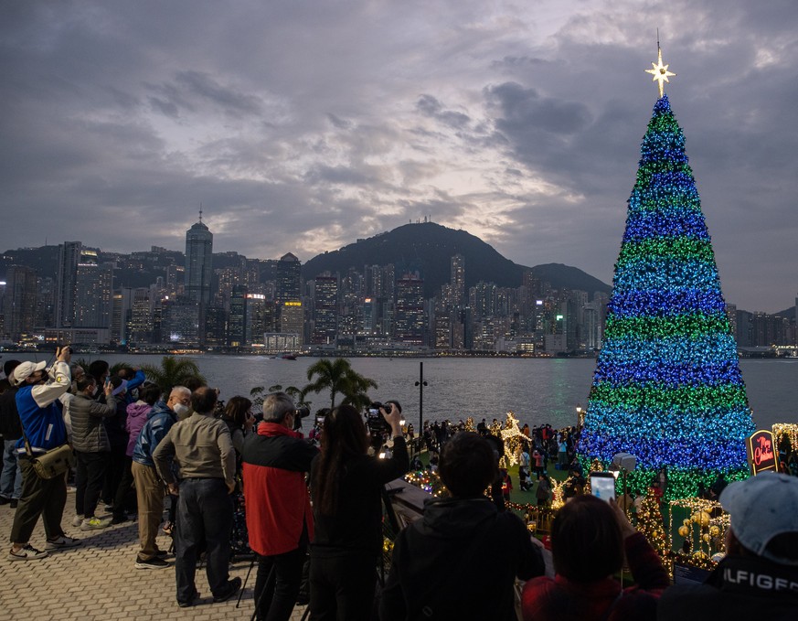 epa10361787 People take photos of a Christmas tree in Hong Kong, China, 12 December 2022. The tree and decorations, set in the West Kowloon Cultural District and Victoria Harbour, are part of the Hong ...