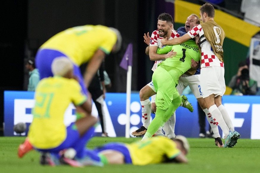 Players of Croatia embrace goalkeeper Dominik Livakovic after defeating Brazil in a World Cup quarterfinal soccer match at the Education City Stadium in Al Rayyan, Qatar, Friday, Dec. 9, 2022. (AP Pho ...