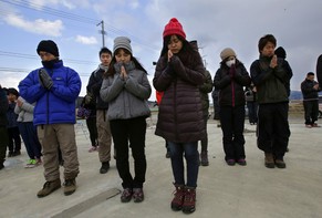 People observe a moment of silence in front of what is left of a disaster control center in an area devastated by the March 11, 2011 earthquake and tsunami, in Minamisanriku, Miyagi prefecture, Tuesday, March 11, 2014. Japan is marking the third anniversary of the devastating earthquake and tsunami that left nearly 19,000 people dead or missing, turned coastal communities into wasteland and triggered a nuclear crisis.  (AP Photo/Shizuo Kambayashi)