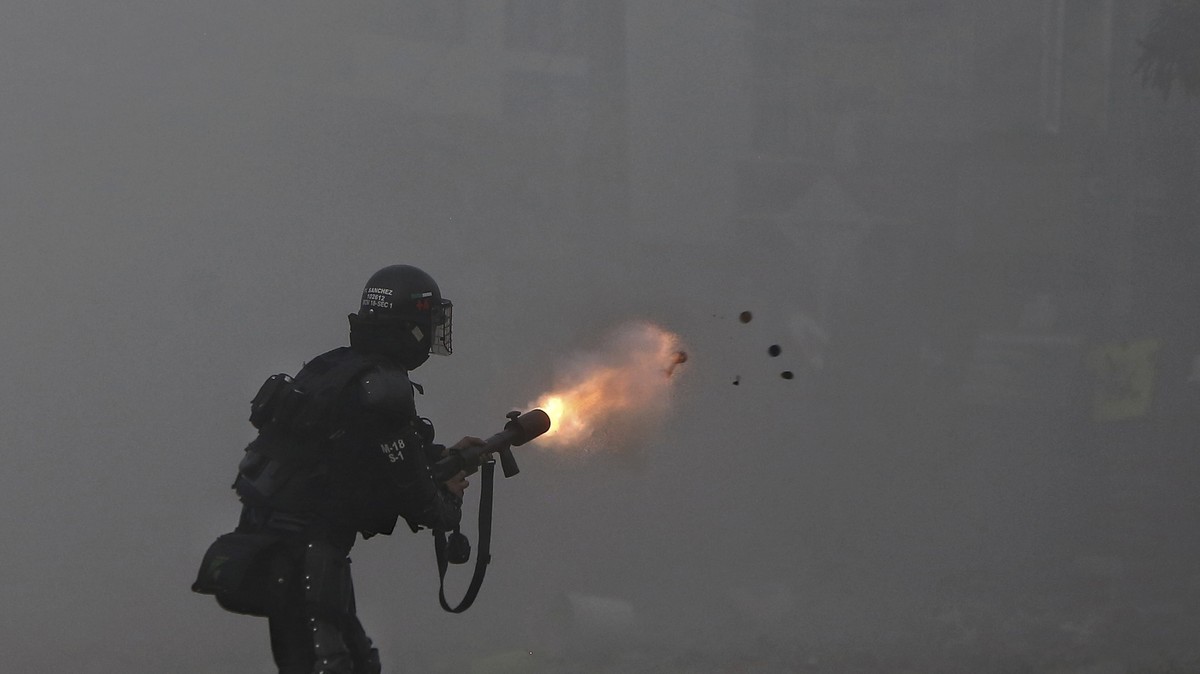 A police officer fires tear gas at protesters during a strike against tax reform in Cali, Colombia, Monday, May 3, 2021. Colombia's President Ivan Duque withdrew the government-proposed tax refor ...