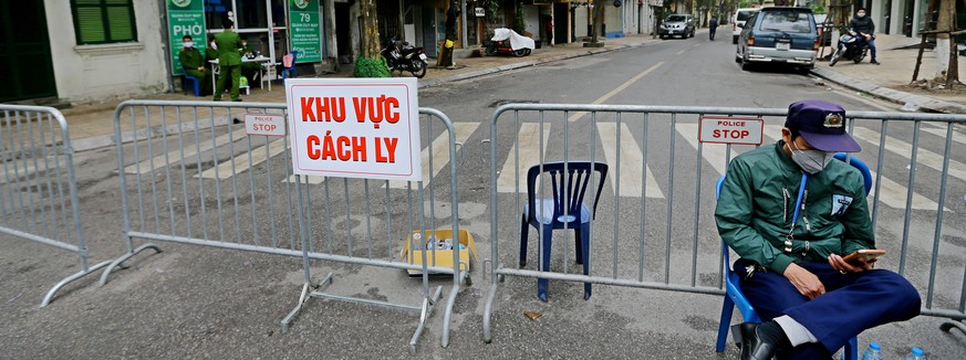 epa08275847 A security man sits in front of a barrier with a sign reading 'Isolation Region' on Truc Bach street in Hanoi, Vietnam, 07 March 2020. A 26-year-old Vietnamese woman recently bac ...
