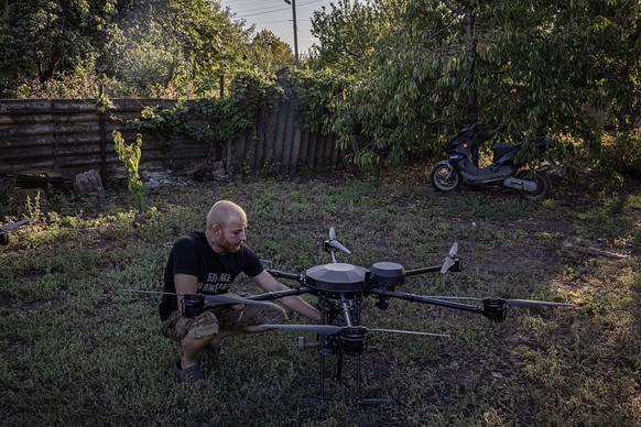 EASTERN UKRAINE - AUGUST 20: A soldier named Dima from Ukraine&#039;s 68th Jaeger Brigade holds an explosive device next to a vampire drone, which is used to drop explosives or food, to shows how it c ...