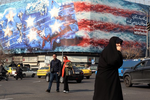 KEYPIX - epa12684293 Iranians walk near a huge anti-US billboard hanging at the Enqelab square in Tehran, Iran, 27 January 2026. The US President Donald Trump renewed threats of military action agains ...
