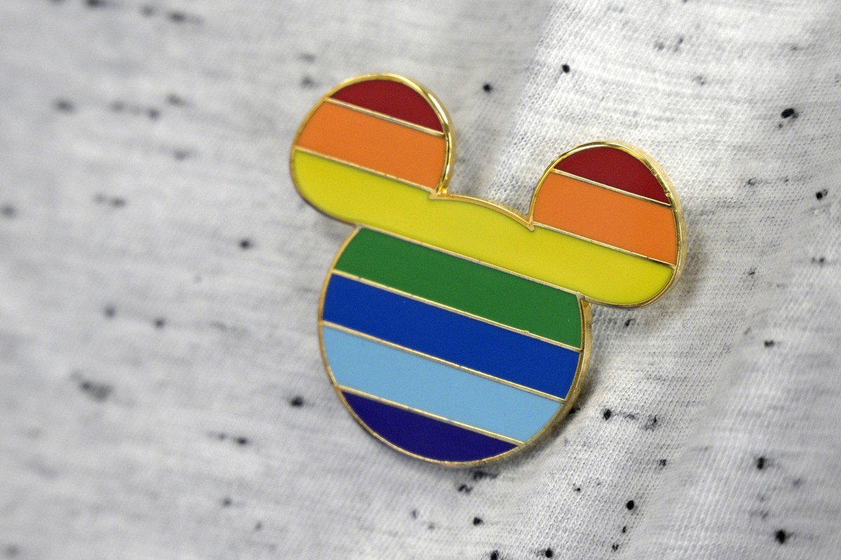 A Disney cast member displays a Mickey Mouse pin on his shirt at The Center, an LGBTQ support organization, while participating in an employee walkout of Walt Disney World, Tuesday, March 22, 2022, in ...