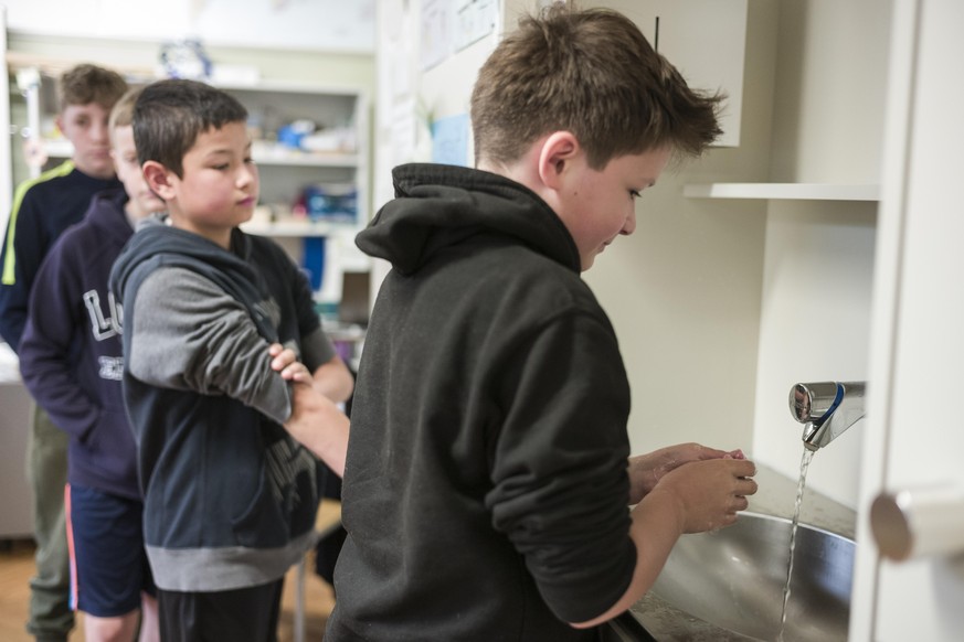 Die Schueler der fuenften Klasse waschen ihre Haende, bevor sie das Klassenzeimmer betreten, am Tag der Wiedereroeffnung der Lorraineschule, am Montag, 11. Mai 2020 in Bern. Die Schulen wurden nach Au ...