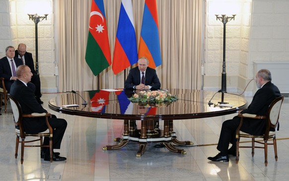 Russian President Vladimir Putin, center, speaks to Azerbaijan&#039;s President Ilham Aliyev, left, and Armenian Prime Minister Nikol Pashinyan, right, during their meeting in the Bocharov Ruchei resi ...