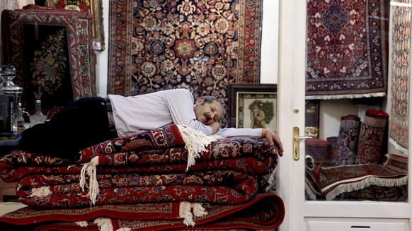 A carpet seller takes a nap at the carpet market in the old main Bazaar in Tehran, Iran, Monday, July 23, 2018. Iranians on Monday shrugged off the possibility that a bellicose exchange of words betwe ...