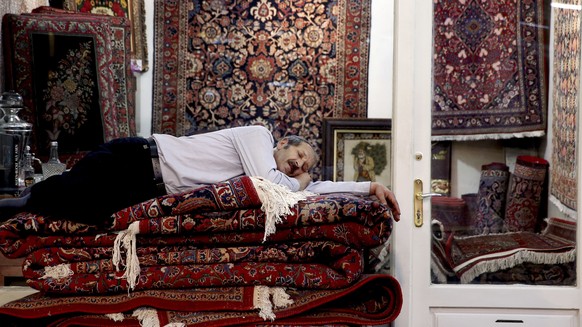 A carpet seller takes a nap at the carpet market in the old main Bazaar in Tehran, Iran, Monday, July 23, 2018. Iranians on Monday shrugged off the possibility that a bellicose exchange of words betwe ...