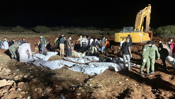 Workers bury the bodies of victims of recent flooding caused by Mediterranean storm Daniel near the city of Derna, Libya, Wednesday, Sept. 13, 2023. Thousands of bodies have been recovered in the days ...