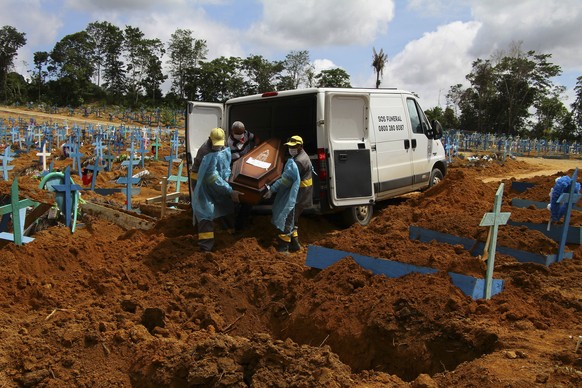 FILE - In this Jan. 6, 2021, file photo, cemetery workers carry the remains of 89-year-old Abilio Ribeiro, who died of the coronavirus, to bury at the Nossa Senhora Aparecida cemetery in Manaus, Amazo ...