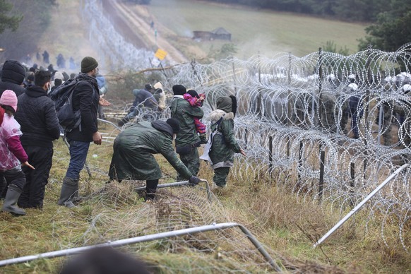 Migrants from the Middle East and elsewhere break down the fence as they gather at the Belarus-Poland border near Grodno, Belarus, Monday, Nov. 8, 2021. Poland increased security at its border with Be ...