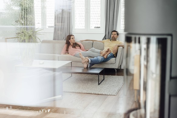 Mature couple relaxing together on sofa while talking in living room model released Symbolfoto property released JOSEF02741