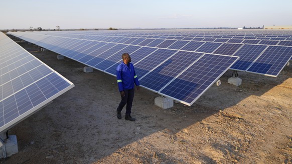 A man walks through a solar farm on the outskirts of Harare, Zimbabwe on Wednesday, Aug. 24, 2022. Access to more and cleaner energy while continuing to grow economically will be a top priority for Af ...